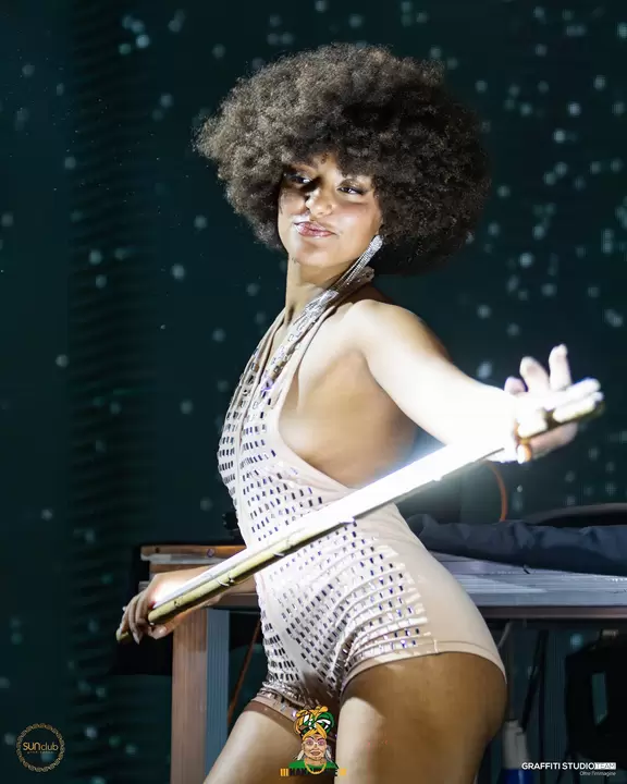 Performer con parrucca afro e tuta argento con bastone luminoso