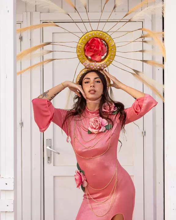 Performer in abito rosa con copricapo a sole dorato