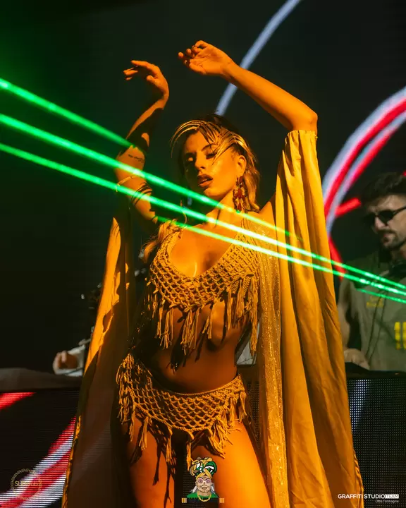 Performer in costume dorato a frange tra i laser verdi