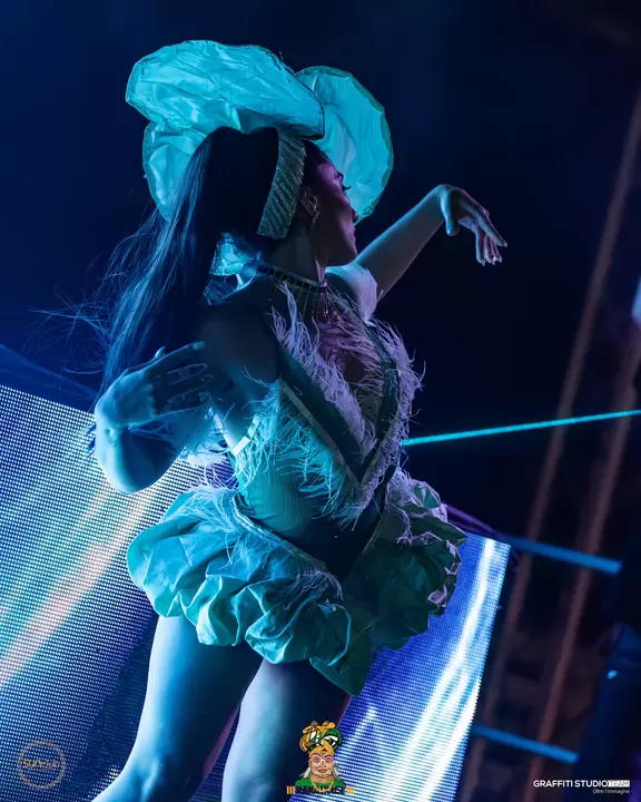 Performer in costume azzurro con piume in posa sul palco