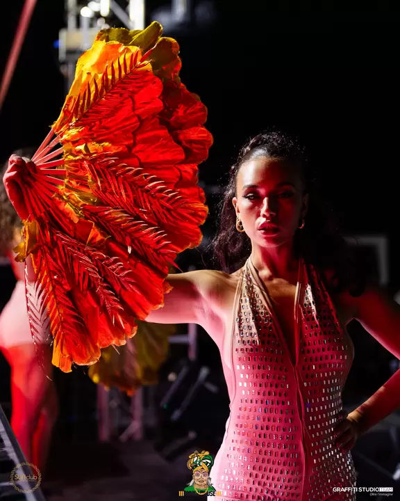 Performer con ventaglio di piume rosse e body di cristalli