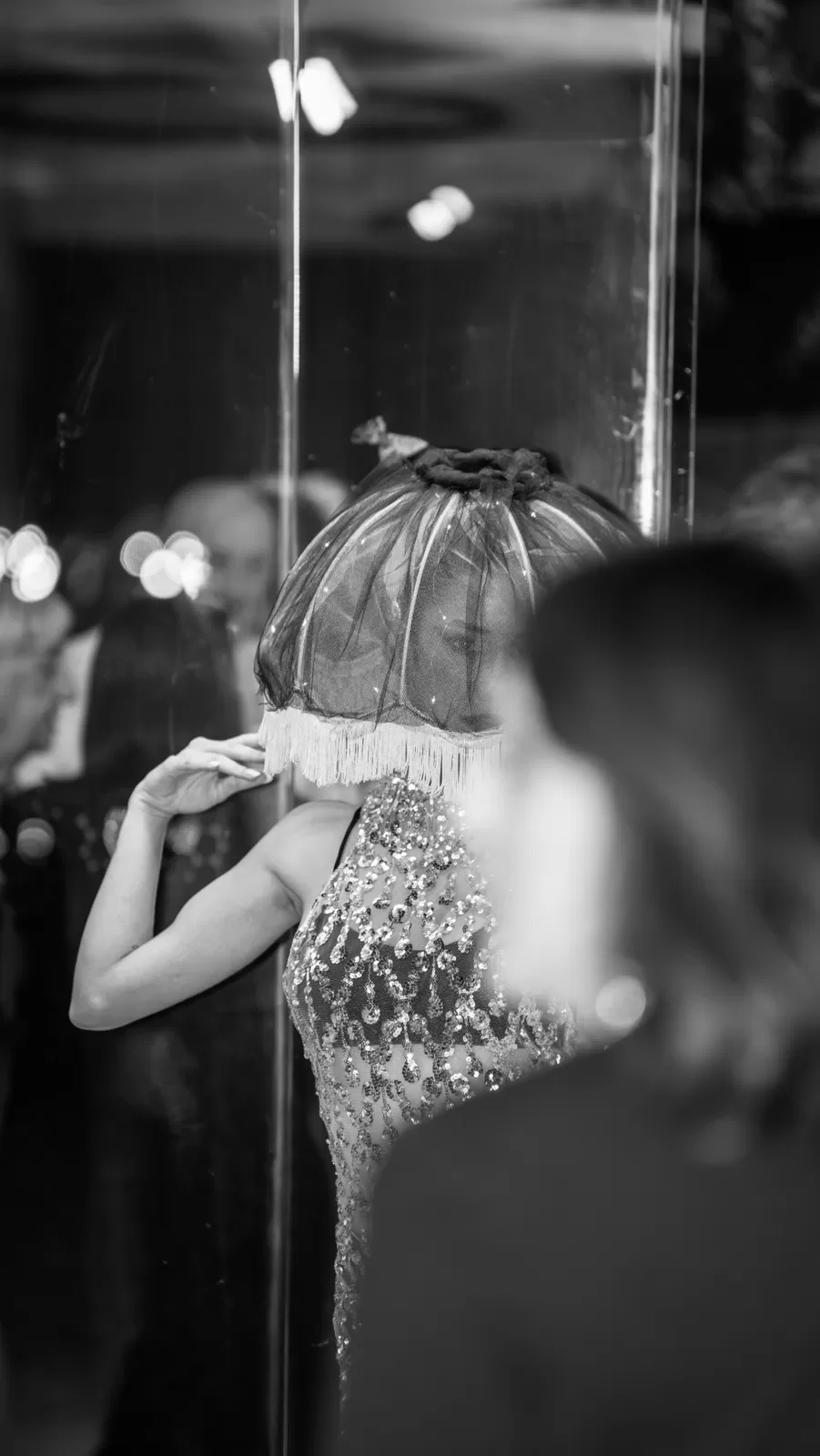 Performer con paralume di tulle e frange e abito di paillettes durante un evento, in bianco e nero