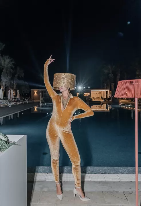 Performer in tuta di velluto dorato con copricapo a cilindro davanti alla piscina