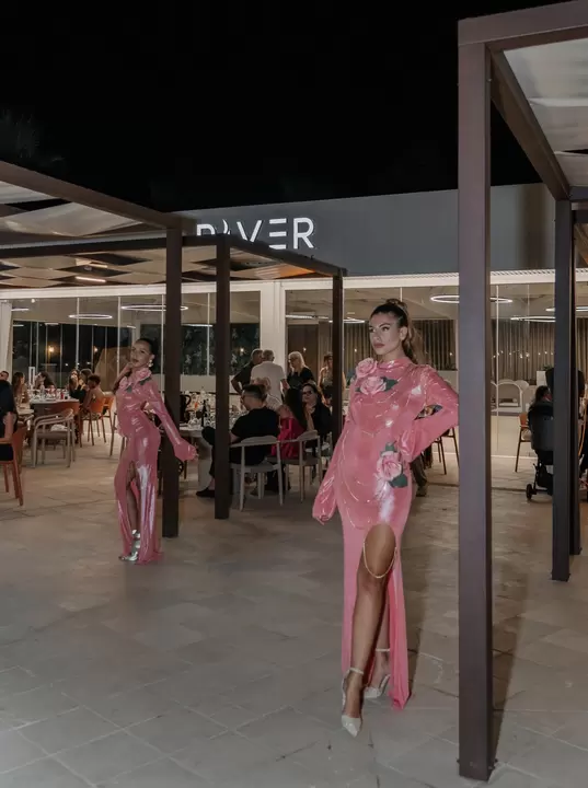 Due performer in abito rosa con rose applicate tra i tavoli di un evento