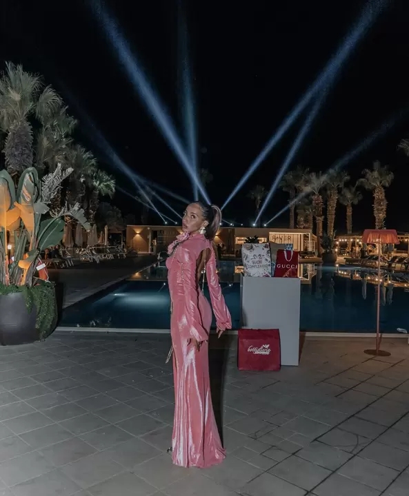 Performer in abito rosa di velluto sotto i fasci di luce di una festa di compleanno