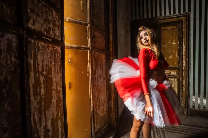 Ballerina con tutù rosso e bianco nella luce di una porta