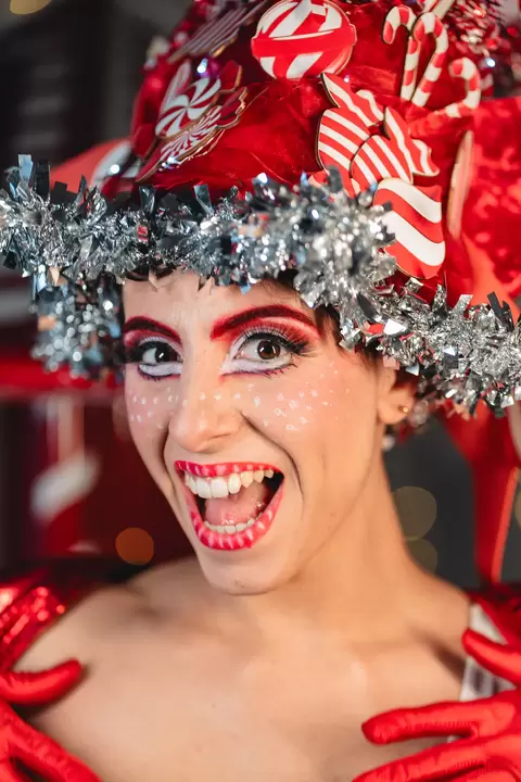 Performer con copricapo di dolciumi che ride, trucco rosso e bianco